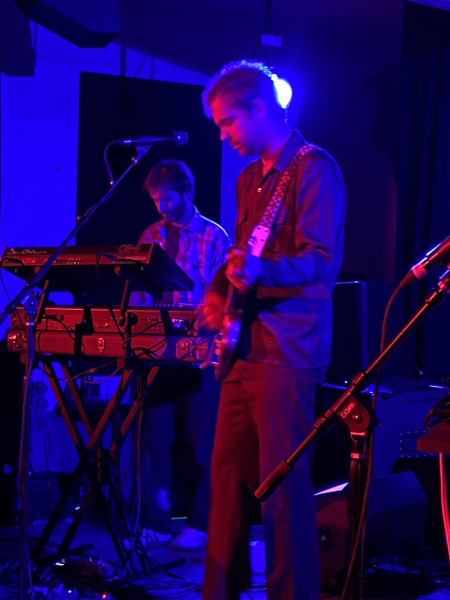 Musician performing onstage under blue and purple lights